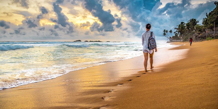 Frau spaziert am Strand in Sri Lanka