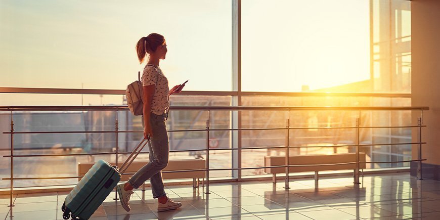 Frau geht mit Reisepass und Bordkarte in der Hand durch den Flughafen