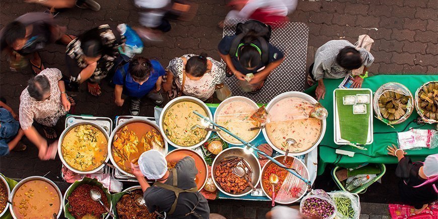 Menschen kaufen Lebensmittel auf einem Straßenmarkt in Thailand