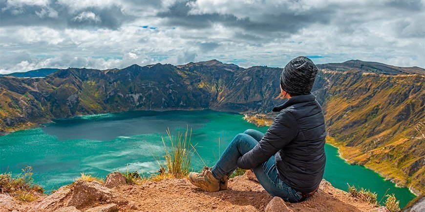 Frau sitzt am Rande des Kratersees Quilotoa in Ecuador.