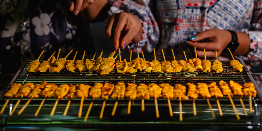 Frauen kochen Moo Satay auf dem Grill