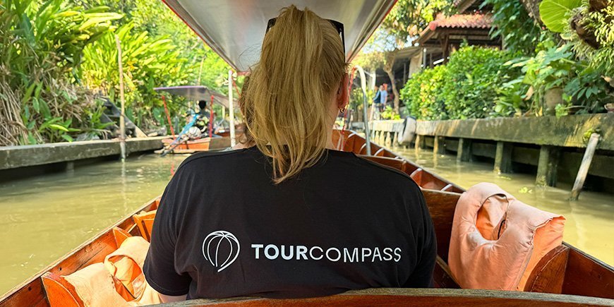 Frau im TourCompass-T-Shirt sitzt mit dem Rücken zugewandt im Boot